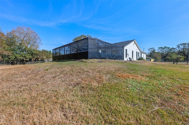 exterior space featuring a yard and glass enclosure