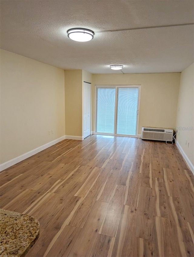 empty room with a textured ceiling and light hardwood / wood-style flooring