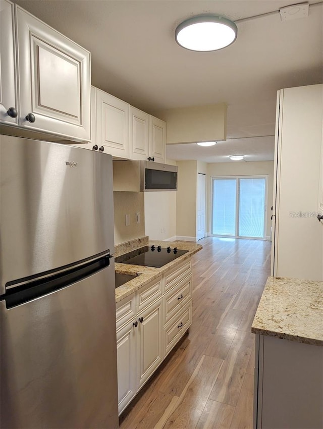 kitchen with white cabinetry, light stone counters, and appliances with stainless steel finishes