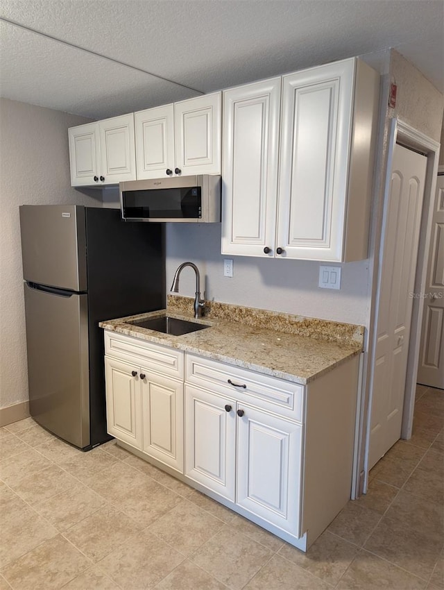 kitchen featuring stainless steel appliances, white cabinetry, and sink