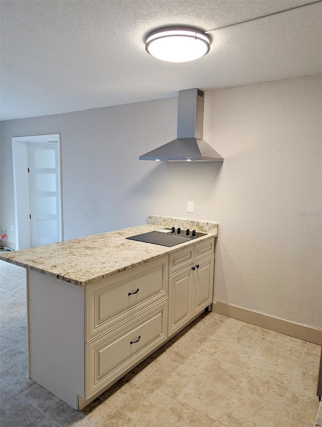 kitchen with black electric cooktop, a textured ceiling, light stone countertops, and wall chimney exhaust hood