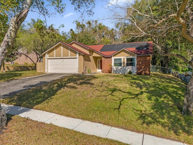 ranch-style home with a garage, a front lawn, and solar panels