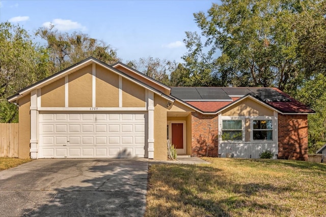 ranch-style home with a garage, a front yard, and solar panels