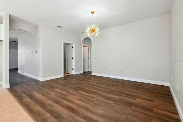 empty room featuring dark wood-type flooring and an inviting chandelier