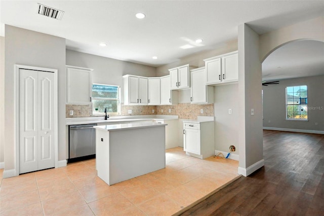 kitchen with a center island, light tile patterned floors, dishwasher, decorative backsplash, and white cabinets