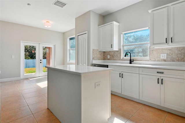 kitchen with tasteful backsplash, plenty of natural light, a kitchen island, and white cabinets