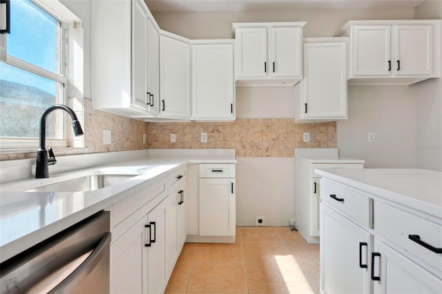 kitchen with sink, light tile patterned floors, white cabinets, decorative backsplash, and stainless steel dishwasher