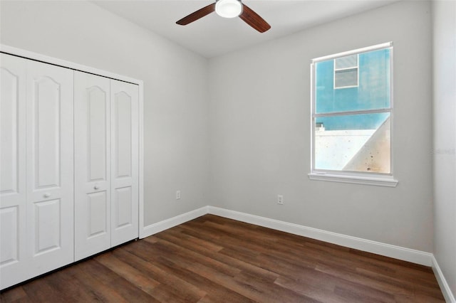 unfurnished bedroom featuring multiple windows, ceiling fan, dark hardwood / wood-style flooring, and a closet