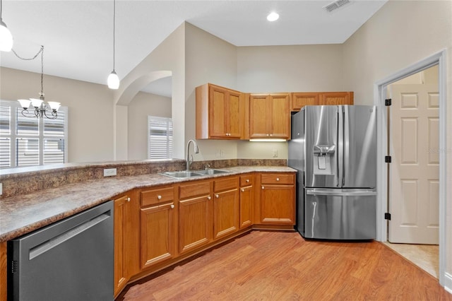 kitchen featuring pendant lighting, stainless steel appliances, sink, and light wood-type flooring