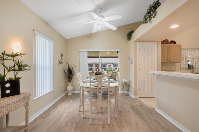 dining room featuring lofted ceiling, ceiling fan, light hardwood / wood-style flooring, and a textured ceiling