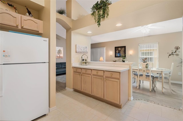 kitchen featuring light tile patterned floors, ceiling fan, light brown cabinetry, kitchen peninsula, and white fridge