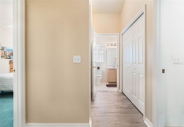 hall with light hardwood / wood-style floors and a textured ceiling