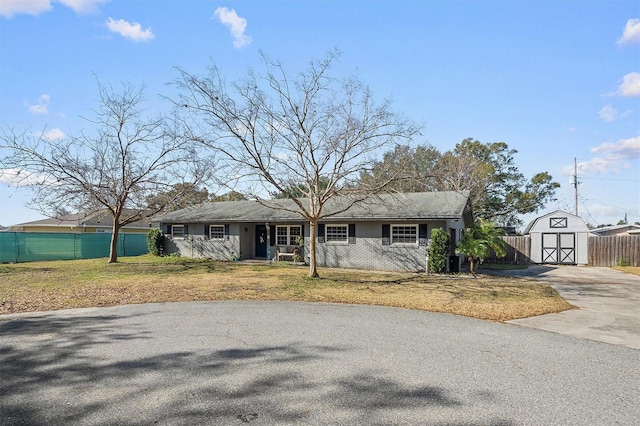 ranch-style house with a storage unit and a front lawn