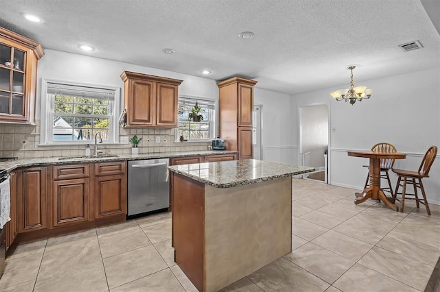 kitchen featuring sink, hanging light fixtures, light stone counters, a kitchen island, and stainless steel dishwasher