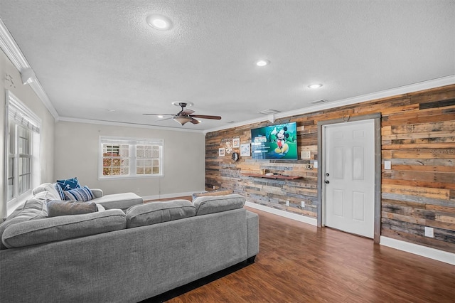 living room featuring crown molding, dark wood-type flooring, ceiling fan, a textured ceiling, and wood walls