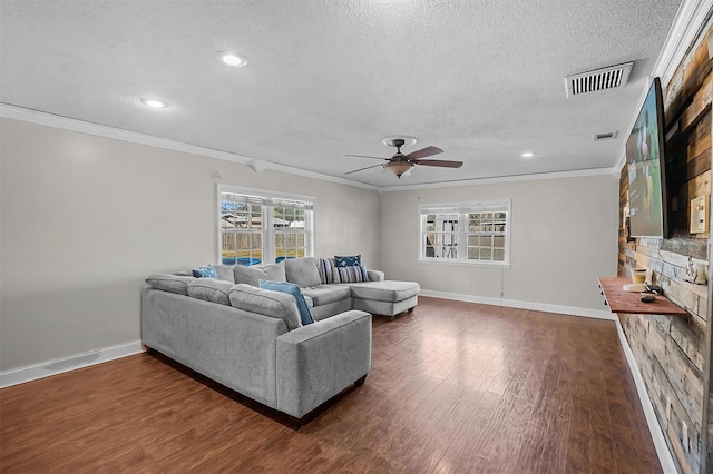 living room with dark hardwood / wood-style flooring, ceiling fan, ornamental molding, and a textured ceiling