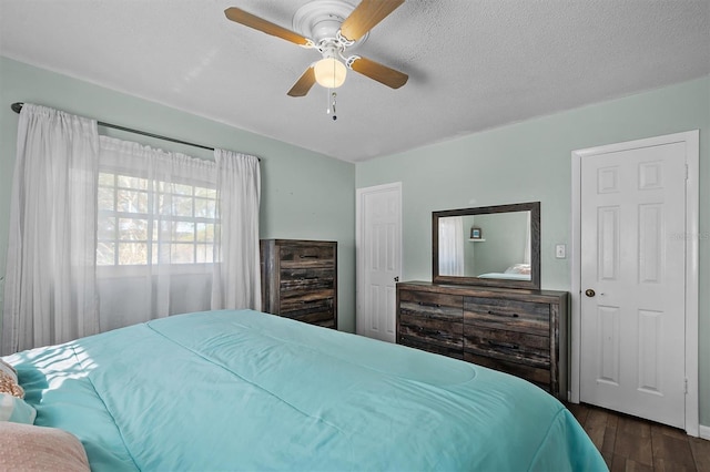 bedroom with ceiling fan, dark hardwood / wood-style flooring, and a textured ceiling