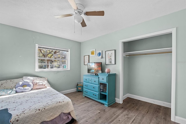 bedroom featuring ceiling fan, a textured ceiling, light wood-type flooring, and a closet