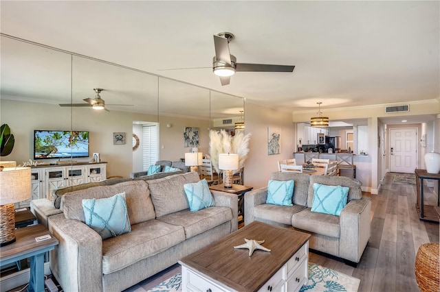 living room with hardwood / wood-style flooring, ceiling fan, and ornamental molding