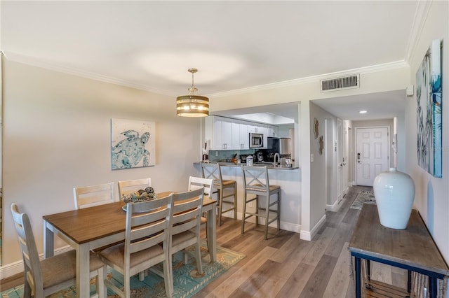 dining space with crown molding and hardwood / wood-style flooring