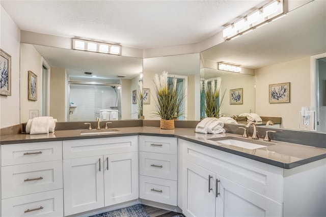 bathroom with vanity, a shower with shower door, and a textured ceiling