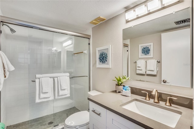 bathroom featuring walk in shower, vanity, toilet, and a textured ceiling