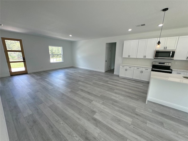 kitchen with stainless steel appliances, white cabinetry, pendant lighting, and light hardwood / wood-style flooring