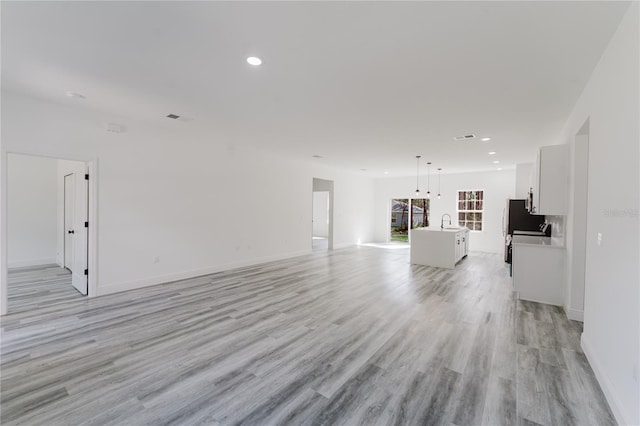 unfurnished living room with sink and light hardwood / wood-style flooring