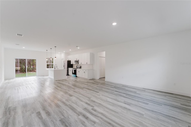 unfurnished living room with sink and light wood-type flooring