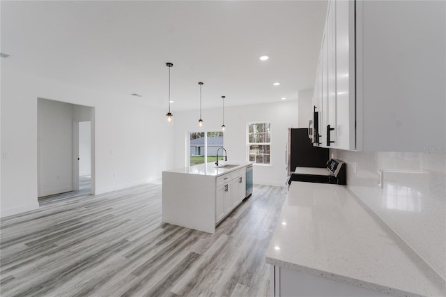 kitchen with sink, white cabinetry, hanging light fixtures, a center island with sink, and appliances with stainless steel finishes