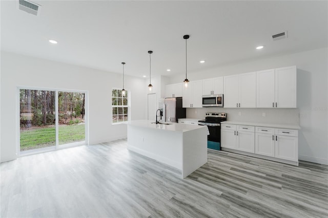 kitchen featuring a kitchen island with sink, hanging light fixtures, stainless steel appliances, and white cabinets