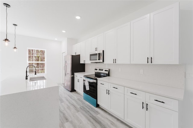 kitchen featuring sink, hanging light fixtures, light wood-type flooring, stainless steel appliances, and white cabinets