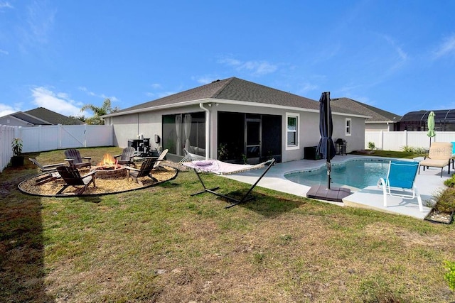 rear view of property with a sunroom, a yard, a fenced in pool, and a fire pit