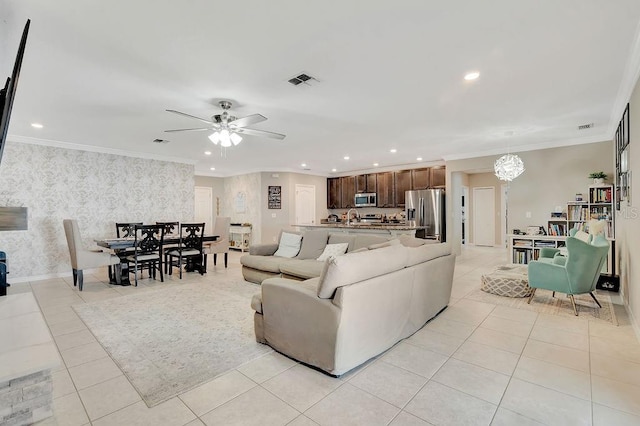 tiled living room featuring crown molding and ceiling fan with notable chandelier