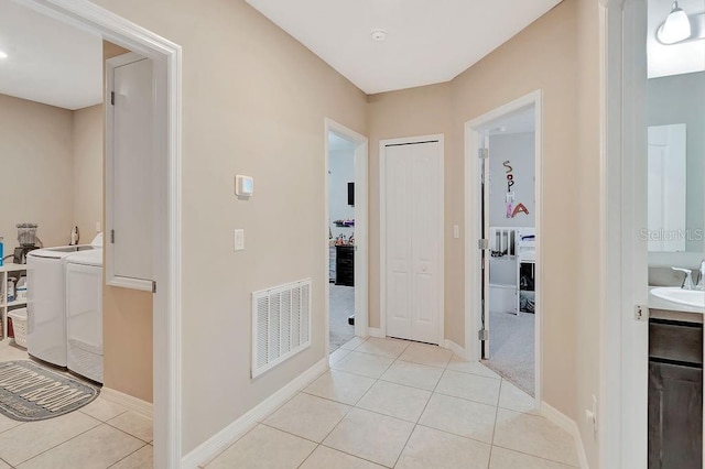 hall with separate washer and dryer, sink, and light tile patterned floors