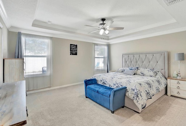 bedroom featuring a textured ceiling, ornamental molding, a tray ceiling, ceiling fan, and carpet