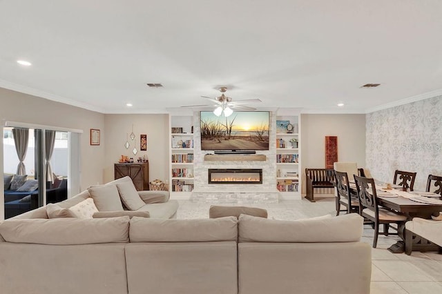 living room featuring a stone fireplace, ornamental molding, light tile patterned floors, ceiling fan, and built in shelves