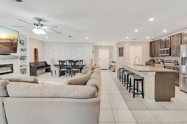 living room with crown molding, sink, light tile patterned floors, and a fireplace