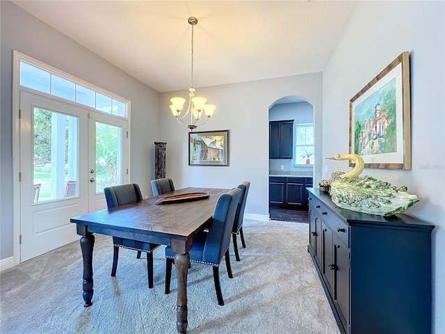 carpeted dining room with an inviting chandelier and french doors