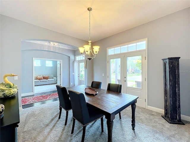 dining space with french doors, light colored carpet, and a chandelier