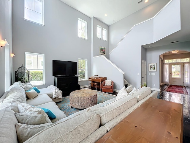 living room with hardwood / wood-style flooring, a towering ceiling, and plenty of natural light