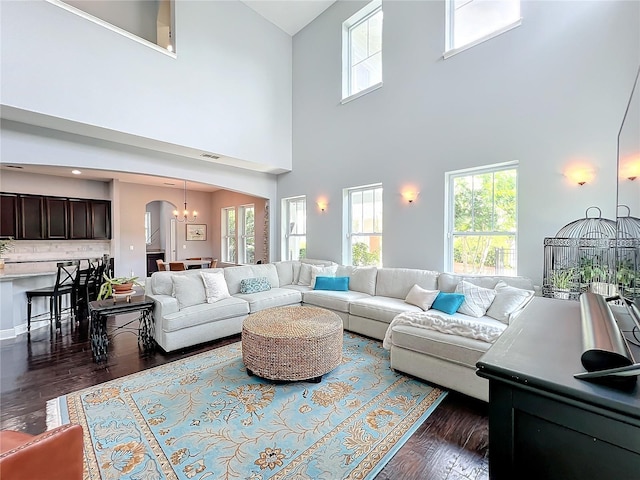 living room with an inviting chandelier, a wealth of natural light, and dark wood-type flooring