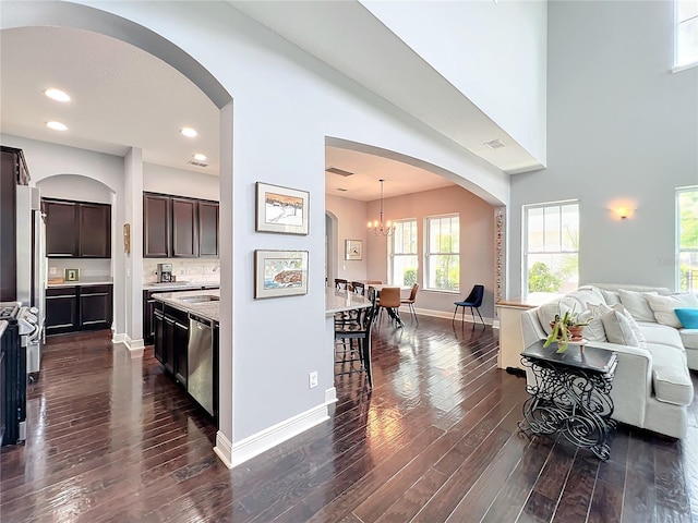 kitchen featuring stainless steel appliances, dark brown cabinetry, dark hardwood / wood-style flooring, decorative light fixtures, and a chandelier