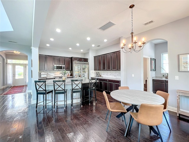 dining area with dark hardwood / wood-style floors, a textured ceiling, and an inviting chandelier