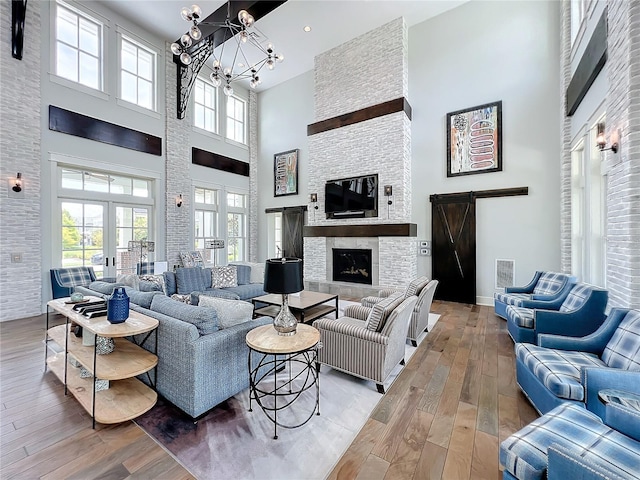 living room featuring a fireplace, a chandelier, hardwood / wood-style flooring, a barn door, and french doors