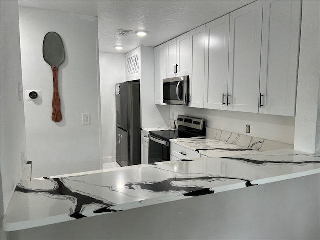 kitchen featuring stainless steel appliances, white cabinetry, and a textured ceiling