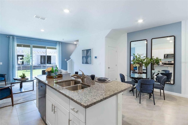 kitchen featuring sink, dishwasher, stone counters, white cabinetry, and a kitchen island with sink