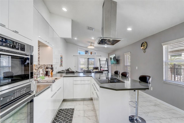 kitchen with white cabinetry, black electric stovetop, stainless steel oven, and a kitchen bar