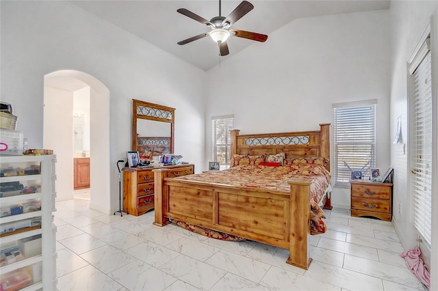 bedroom with ceiling fan, ensuite bath, high vaulted ceiling, and multiple windows