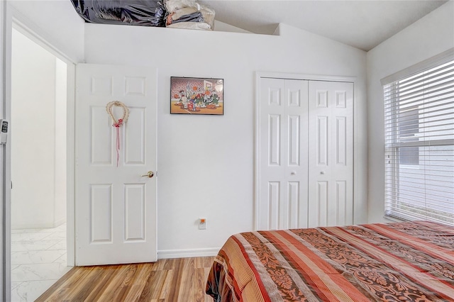 bedroom with vaulted ceiling, a closet, and light wood-type flooring